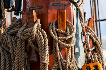 Old wooden sailing ship. Old wooden mast with sails. Sailing ship. Ships' rope on old boat. Wooden block and ropes.