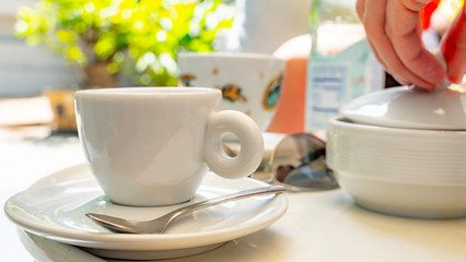 Herbal tea in green cup, honey and yellow teapot on white wooden table in cafe. A cup of hot tea with steam. Natural light.
