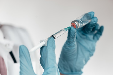 Close-up image of hands with a syringe with vial.