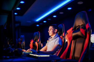 Young gamer playing video game in modern playroom with blue neon light.