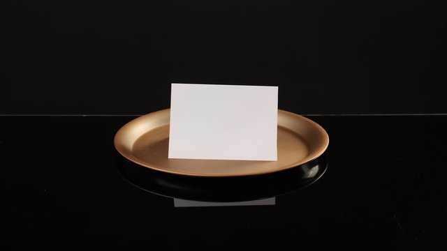 Male waiter opening tray with sheet of paper on dark background