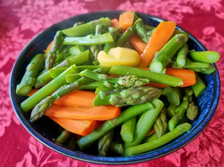 Steaming bowl of asparagus, carrot and butter