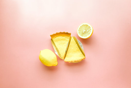 Lemon pies with half and whole fresh lemons on pink background