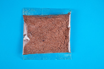 Flax porridge in a transparent plastic bag on a blue background. Top view.