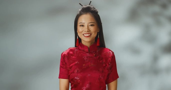 Portrait shot of Asian young cheerful beautiful woman in beauty of Asia style smiling to camera. Japanese pretty stylish female in red cheongsam with smile.