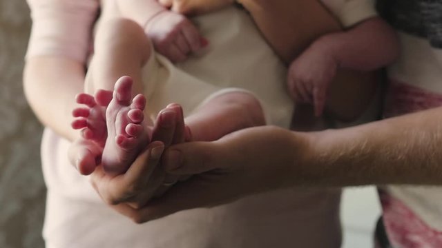 feet of a newborn in the hands of parents close-up. Mom and Dad are holding a newborn in their arms