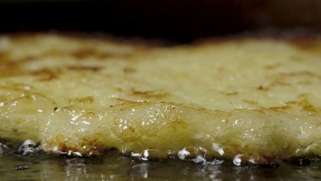 Potato pancakes draniki are fried in vegetable oil in a pan, macro shot