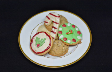 Home made Christmas cookies on a plate against a black background.