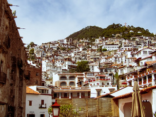 View of the village with white houses with red roofs and balconies with multicolored flowers are an attraction for tourists in Taxco de Alarcon, Guerrero, Mexico.