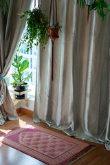 Pray and worship area room at home for Muslim. Islamic prayer rug with hanging green plants with sunlights coming from the window. Beautiful Interior Design.