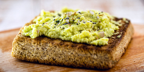 Avocado on crunchy toast, with seasonings and spices. Vegan bread made from organic yeast.