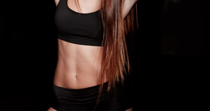 Close up girl shows sports stomach. Healthy fitness and eating lifestyle concept. Fitness sporty woman showing her well trained body, isolated over black background. 4K