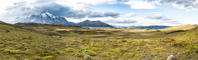 Fototapeta na wymiar fotografía panorámica de una zona montañosa colorida, con montañas enormes a su alrededor y cielo con pequeñas nubes. Parque Torres del Paine, Chile 