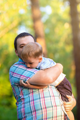 The father and the son. A man holds his son in his arms summer in the forest. Father's day....