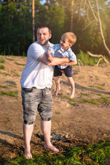 The father and son. The father throws his son on the beach. Father's day. Vertical photo