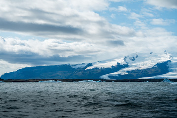Fototapeta na wymiar Icebergs Crashing Into Shore of Black Sand Beach - Diamond Beach, Iceland
