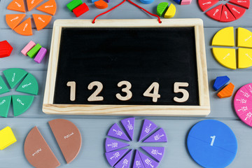 Close up of blackboard with numbers and Multicolored math fractions on the on gray wooden table....