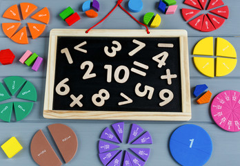 Close up of blackboard with numbers and Multicolored math fractions on the on gray wooden table. Interesting math for kids background. Education, back to school concept