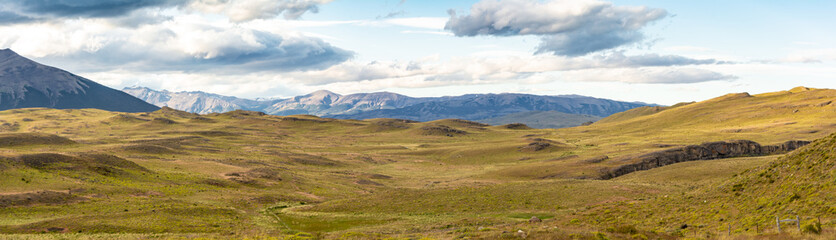 fotografía panorámica de una zona montañosa colorida, con montañas enormes a su alrededor  y cielo con pequeñas nubes. Parque Torres del Paine, Chile