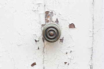 The bronze round handle on the old white front door