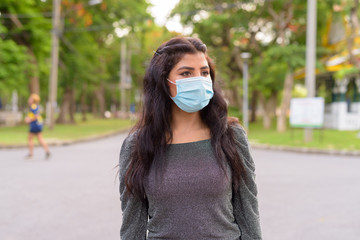 Young Indian woman with mask thinking at the park outdoors