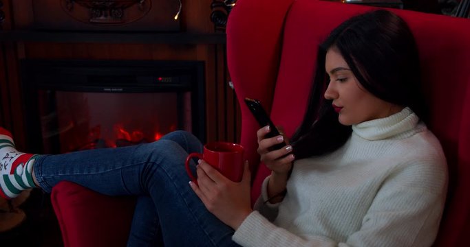 Caucasion youg woman using a mobile phone during Christmas time at home 4k slow motion