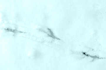 Imprints of bird paws on the snow close-up. Top view. Natural winter background blue color toned
