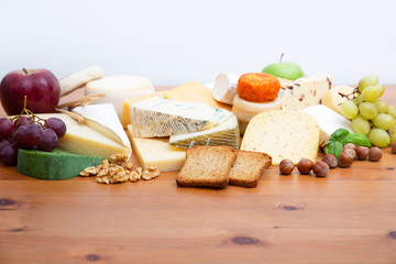 Cheeses and snacks set. Toasted slices of bread, apples, bunches of grapes and nuts on brown wooden table. Closeup, copy space. Gourmet or rustic food concept