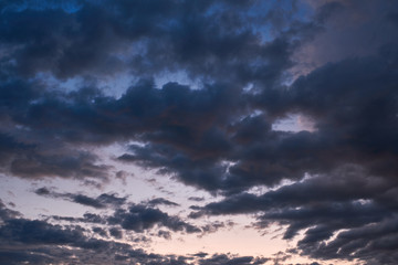Sunrise against the background of dark gray clouds of the lower tier