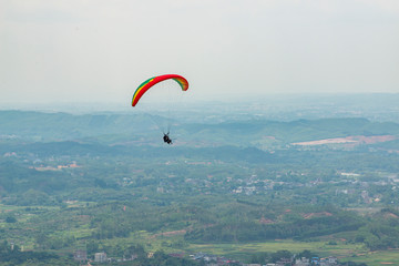 Outdoor city green hill scenery and paragliding