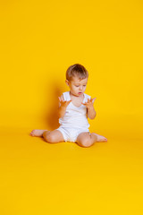 little boy in a t-shirt and underwear sitting on an orange-yellow background