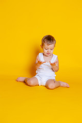little boy in a t-shirt and underwear sitting on an orange-yellow background