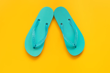 Flip flops in blue on a yellow background, flat lay. Summer beach shoes. Vacation and travel...