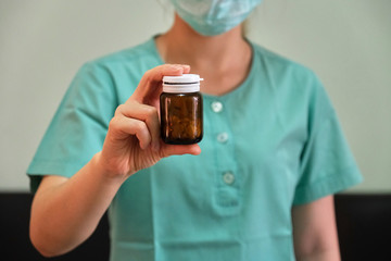 A female nurse with a brown medicine bottle in her hand
