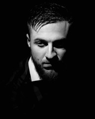 Obraz premium Closeup portrait of confident serious guy on dark background. image in black and white conversion