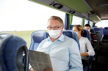 tourism, pandemic and health care concept - senior man wearing face protective medical mask for protection from virus disease reading newspaper in travel bus