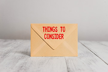 Handwriting text writing Things To Consider. Conceptual photo think about carefully especially in making decisions Closed standing rectangular colored envelope old wooden vintage background