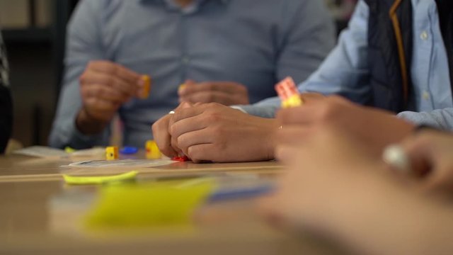 Caucasian hands pull apart interlocking plastic bricks sitting at table, rack and selective focus slow motion