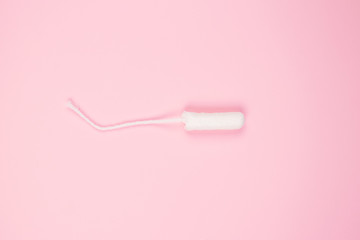 Clean cotton tampon on trendy pink background with copyspace for your text - critical days and menstruation concept. Flat lay minimalistic composition for Menstrual Hygiene Day concept