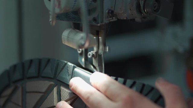 worker sewing shoes on footwear manufacture with machinery