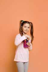 Girl with a felt-tip pens stands on a pink background in daily clothes