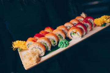 Hand Waiter holding Set Delicious fresh Sushi slate plate Sushi Rolls Warm Ebi Sake Unagi, Japanese raw fish in traditional restaurant. Philadelphia flesh Rolls served Japan bar.   