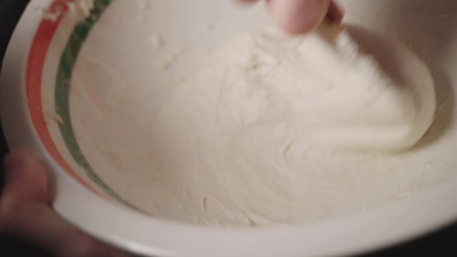 Hand Mixing A Sticky Flour On A Bowl With A Spoon - Closeup Shot