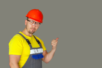 Builder, foreman, in protective clothing, a helmet, a reflective jacket and glasses looks at  the concrete wall..