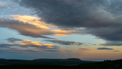 Lenticular clouds light up yellow as the sun sets near The Yorkshire Dales fell of Penyghent,Yorshire,UK