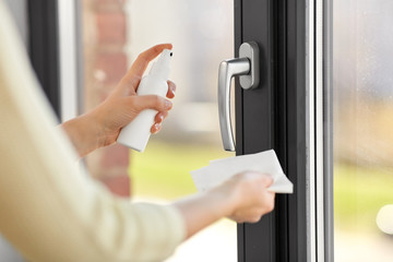 hygiene, health care and safety concept - close up of woman hands cleaning window handle surface...