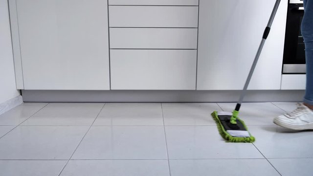 Woman washing white kitchen floor with special swob, cleaning service, close-up