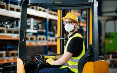 Man worker forklift driver with protective mask working in industrial factory or warehouse.
