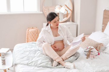 Obraz na płótnie Canvas Beautiful pregnant woman reading book at home