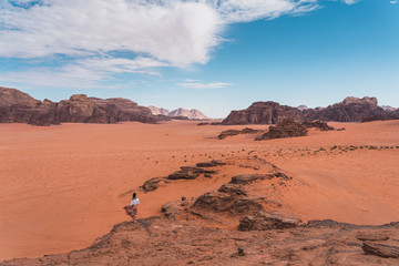 Fototapeta na wymiar A woman traveller standing on rock top of mountain and looking to Wadi Rum desert, Jordan, Arab